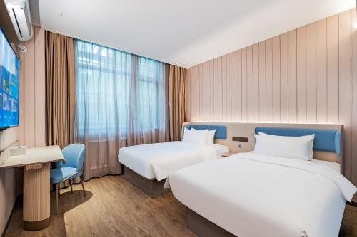 a hotel room with two beds and a table and a desk at Hanting Hotel Beijing Zhongguancun Xueyuan Bridge Subway Station in Beijing