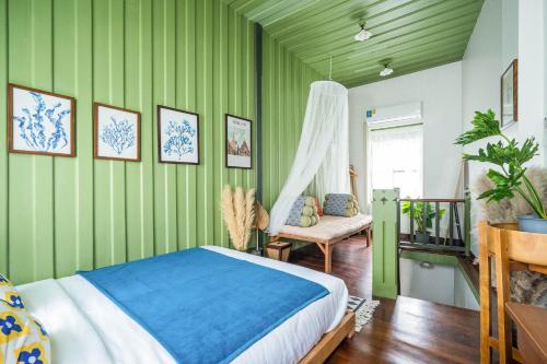 a bedroom with green walls and a bed and a chair at Baan Lek Tee 6 - Chinatown near Yaowarat and MRT in Bangkok