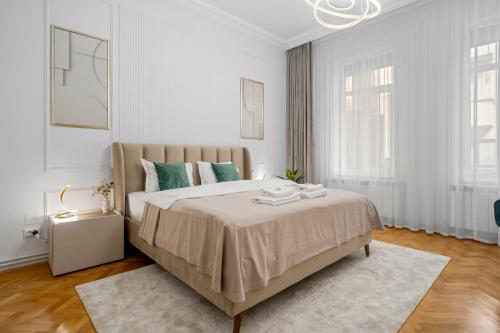 a white bedroom with a large bed with green pillows at Central Luxury Apartments with Private Garden & Parking in Bucharest