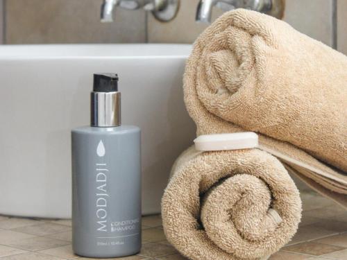 een fles zeep en een handdoek naast een badkuip bij Cozy Corner in Bloemfontein