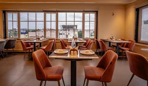 a restaurant with tables and chairs and windows at Hotel Lake Metro in Udaipur