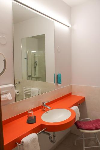 a bathroom with a sink and a large mirror at Vivea Hotel Bad Goisern in Bad Goisern