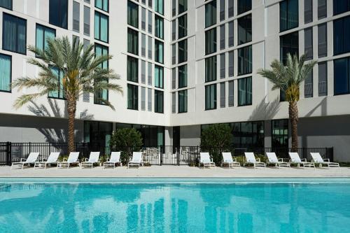 a swimming pool in front of a building with palm trees at AC Hotel by Marriott Tampa Airport in Tampa