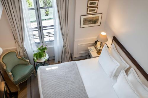 a bedroom with a bed and a chair and a window at Hotel Du Quai Voltaire in Paris