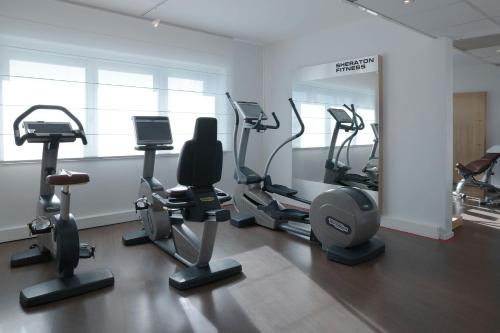 a gym with treadmills and ellipticals in a room at Sheraton Paris Charles de Gaulle Airport Hotel in Roissy-en-France