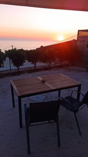 a wooden table and a chair with the sunset in the background at Sun Meets Sea in Athanion