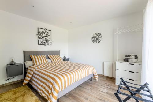 a white bedroom with a bed and a dresser at Kerwall - Maison d'hôtes in Malville