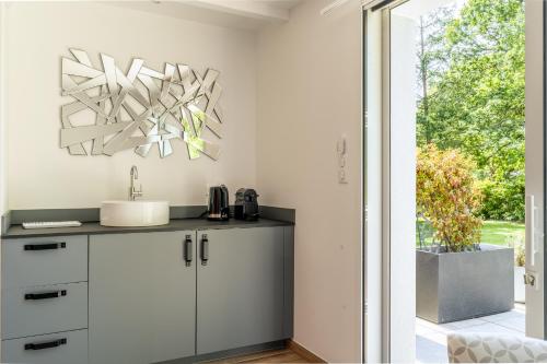 a white kitchen with a sink and a mirror at Kerwall - Maison d'hôtes in Malville