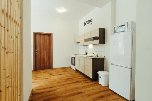 a kitchen with a refrigerator and a wooden floor at Apartmány J&J in Šumperk