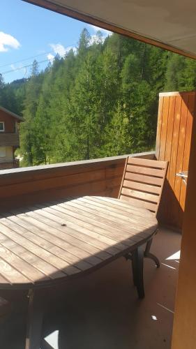 a wooden bench on a balcony with a large window at Terrasses de Labrau - piscine in Allos