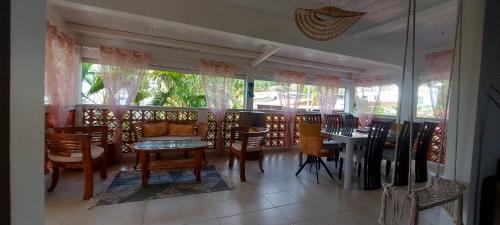 a dining room with tables and chairs and windows at Villa bord de mer - Piscine privée in Les Trois-Îlets