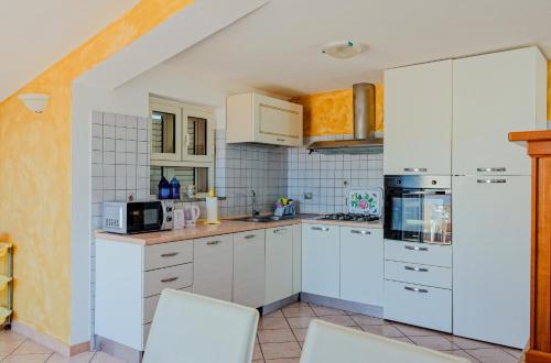 een keuken met witte kasten en witte apparaten bij Mermaid in Cala Gonone