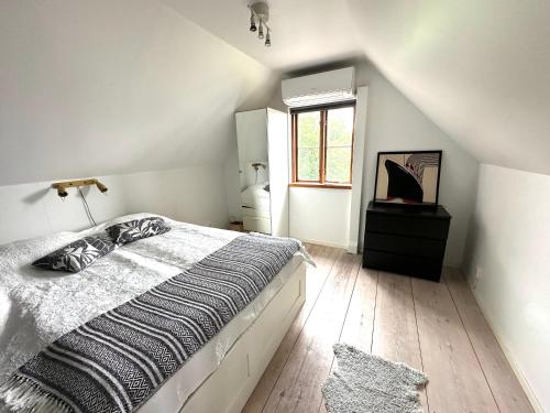 a white bedroom with a bed and a window at Genuint hus i Höganäs hamn in Höganäs