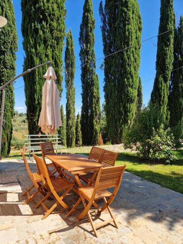 a wooden table and chairs with a umbrella and trees at Borgo Melograno in Chiusi