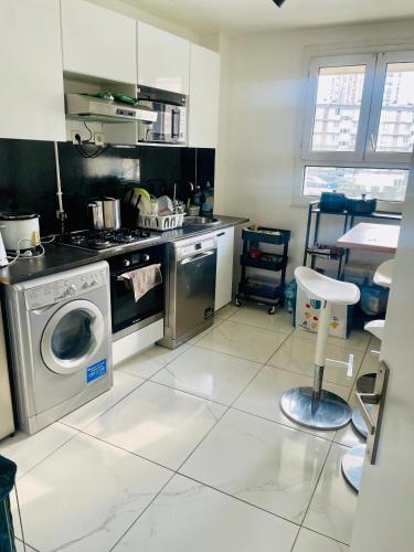 une cuisine avec une cuisinière et une machine à laver dans l'établissement Chambre cosy proche de l'aeroport CDG, à Aulnay-sous-Bois