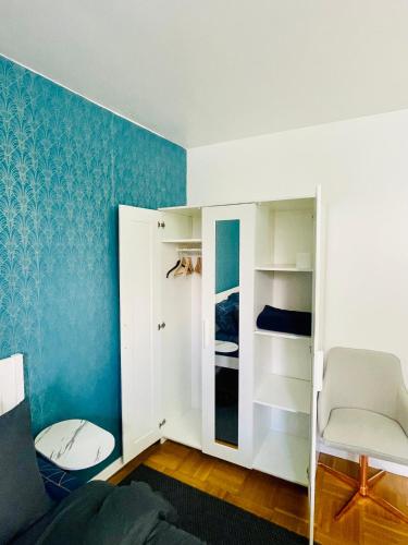une chambre avec un mur bleu et un placard blanc dans l'établissement Chambre cosy proche de l'aeroport CDG, à Aulnay-sous-Bois