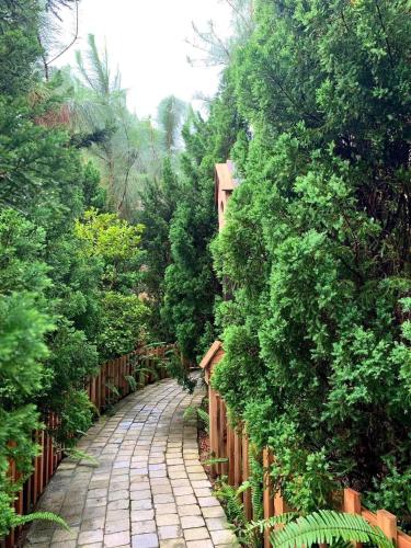 a stone path in a garden with a wooden fence at Khu nghỉ dưỡng Ba Hạt Dẻ in Sóc Sơn