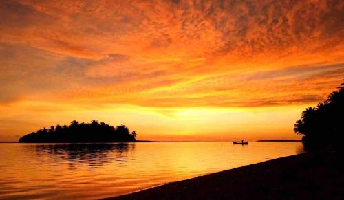 a sunset over a body of water with a small island at Rihiveli inn 