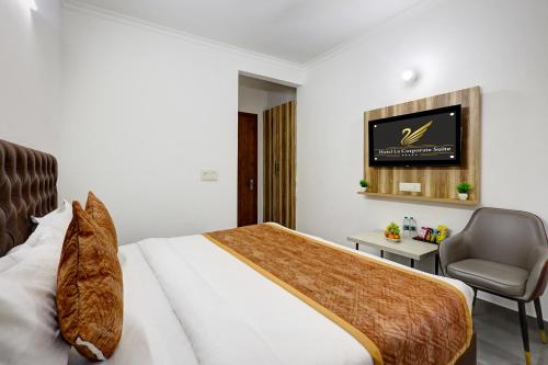 a bedroom with a bed and a chair and a television at FabHotel La Corporate Suite in Noida