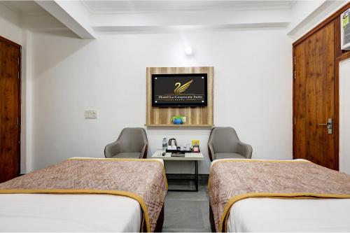a room with two beds and a table and a tv at FabHotel La Corporate Suite in Noida