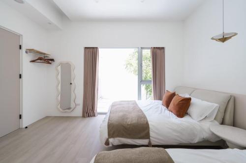 a white bedroom with a bed and a large window at 微風徐徐 Breezy Stay & 漫步阿里 Annie's Home in Zhongpu
