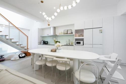 a white dining room with a white table and chairs at 微風徐徐 Breezy Stay & 漫步阿里 Annie's Home in Zhongpu