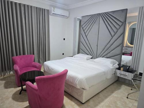 a hotel room with a bed and two pink chairs at شركة فؤاد علي العزي للشقق المخدومة in Taif