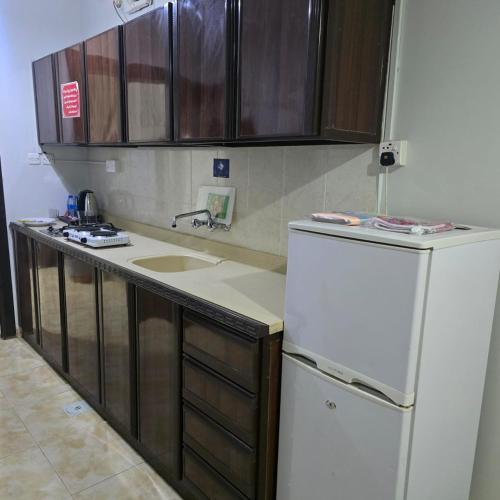 a kitchen with a white refrigerator and wooden cabinets at شركة فؤاد علي العزي للشقق المخدومة in Taif
