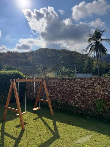 a swing set in front of a stone wall at Casa Samudra - charming & spacious villa by the sea surrounded by nature in Selong Belanak