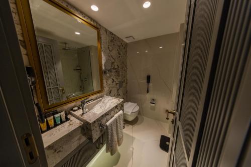 a bathroom with a sink and a toilet and a mirror at Chamada Girne Hotel Spa and Casino in Kérynia