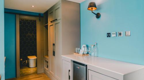 a kitchen with a white counter and a blue wall at H Hotel El Nido - Vegan Friendly Hotel Managed by H Hospitality Group in El Nido