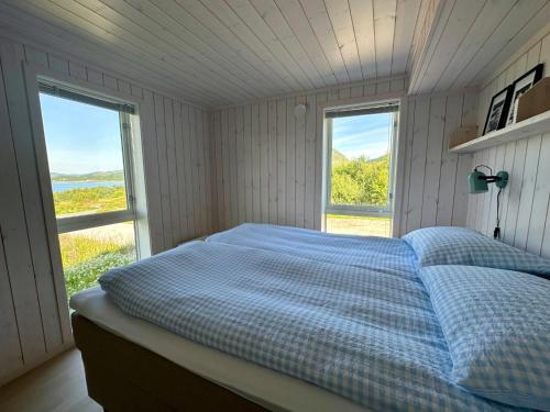a bed in a room with two windows at Sea Pearl Lodge in Leknes