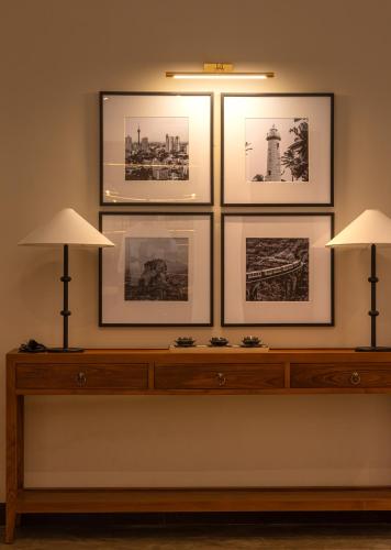 a shelf with three pictures on a wall with two lamps at Granny's House in Colombo