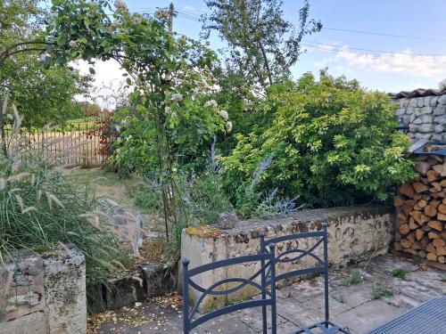 a blue chair in a garden with a stone wall at LES COTEAUX DE VIGNY in Champagne-de-Blanzac