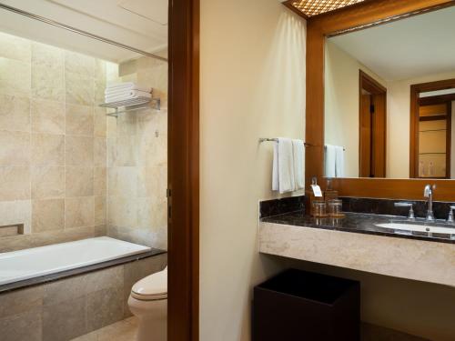 a bathroom with a sink and a toilet and a mirror at Ayodya Resort Bali in Nusa Dua