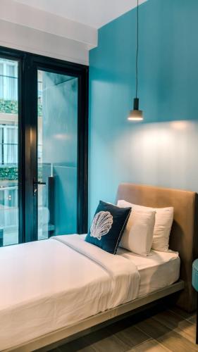 a bedroom with a bed with a blue wall at H Hotel El Nido - Vegan Friendly Hotel Managed by H Hospitality Group in El Nido