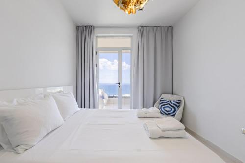 a white bedroom with a large white bed and a chair at Villa Belle Azure in Dhërmi