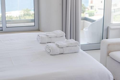 three towels on a bed in a hotel room at Villa Belle Azure in Dhërmi