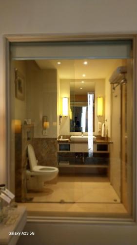 a bathroom with a toilet and a sink and a mirror at Efcee Sarovar Premiere Bhavnagar in Bhavnagar
