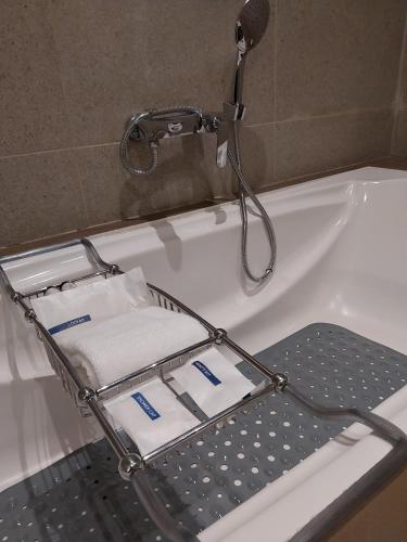 a bath tub with a tray in front of a shower at Efcee Sarovar Premiere Bhavnagar in Bhavnagar