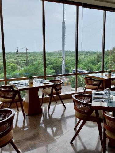 a restaurant with tables and chairs and a large window at Efcee Sarovar Premiere Bhavnagar in Bhavnagar