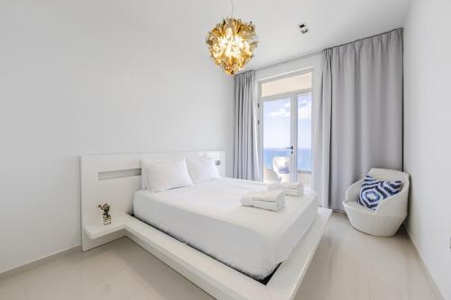 a white bedroom with a large bed and a chandelier at Villa Belle Azure in Dhërmi