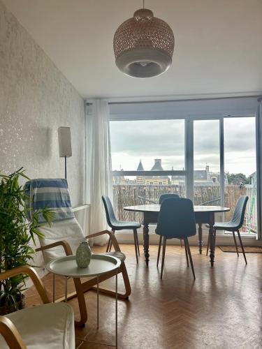 - un salon avec une table, des chaises et une grande fenêtre dans l'établissement Appartement 2 minutes de la plage, à Luc-sur-Mer