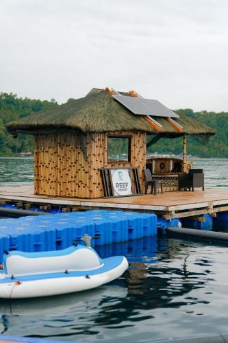 a small hut on the water with a boat in the water at Reef Resort - Mount Apo View Unit B2 in Kaputian