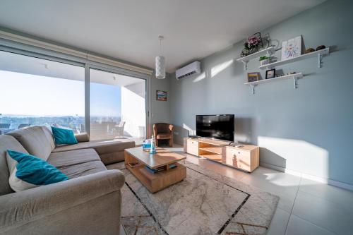 a living room with a couch and a tv at Majestic Sunset Salt Lake Views 300m From Beach in Larnaka