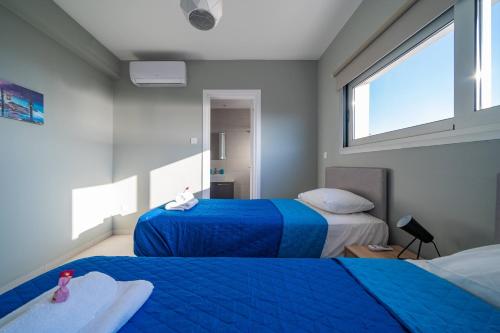 a bedroom with two beds with blue sheets and a window at Majestic Sunset Salt Lake Views 300m From Beach in Larnaka