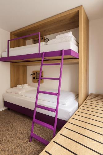 two bunk beds with a purple ladder in a room at Hotelkonkurrenz Hostel in Nürnberg