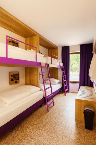 a room with three bunk beds and a window at Hotelkonkurrenz Hostel in Nürnberg