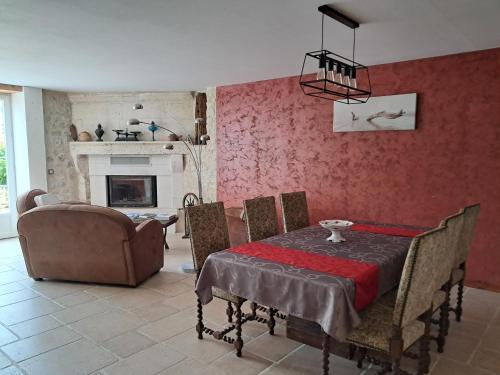 a dining room with a table and chairs and a fireplace at LES COTEAUX DE VIGNY in Champagne-de-Blanzac