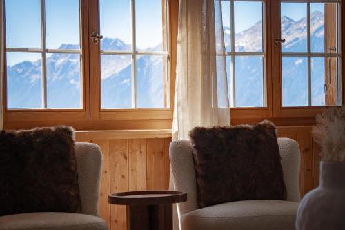 a room with two chairs and windows with mountains at Hidden Retreats The Signature in Brienzwiler